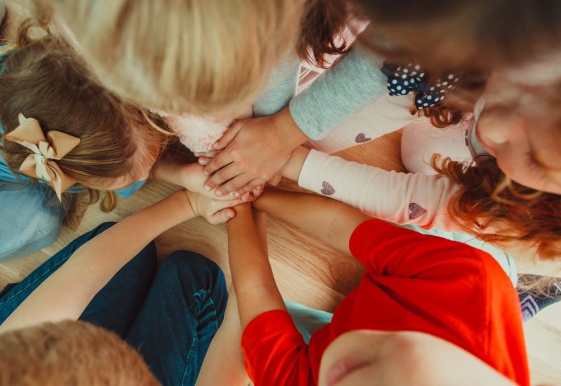 Group of children putting their hands together Group of children putting their hands together indoors, friedly concept