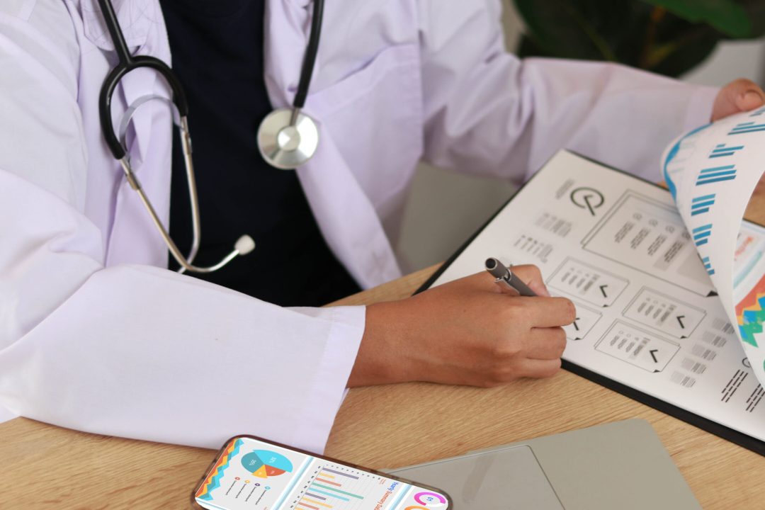 Professional doctor reviewing medical reports and analytics charts on clipboard, using data-driven insights for healthcare planning, diagnosis, and performance monitoring in modern clinic setting.